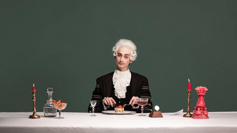 Old-fashioned Frenchmen with wig eating fancy food