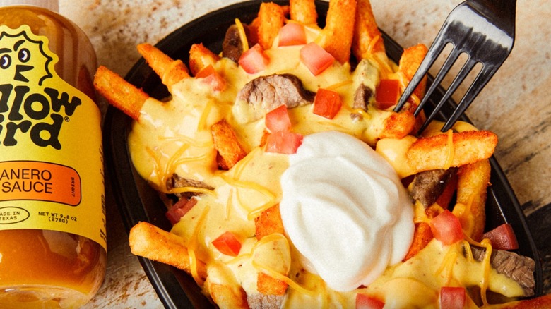 plate of yellowbird nacho fries beside hot sauce bottle