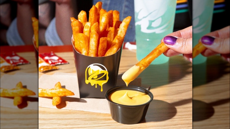 Hand dipping nacho fry into cheese dipping sauce