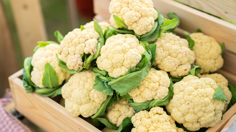 cauliflower with green leaves in a wooden crate