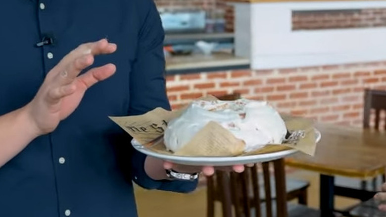 man holds large cinnamon roll