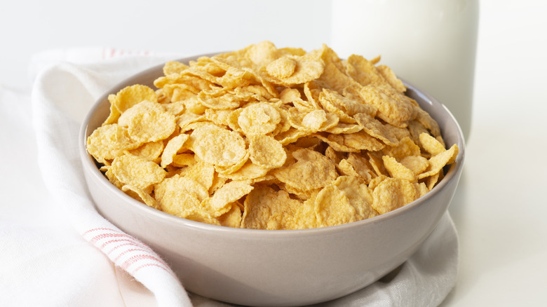 Cornflakes in bowl next to milk