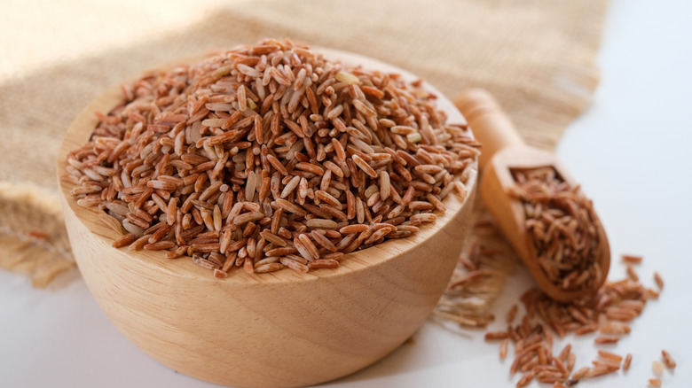 Wooden bowl and scoop of brown rice