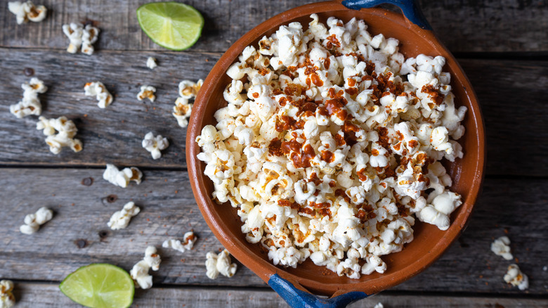 bowl of popcorn with hot sauce and limes