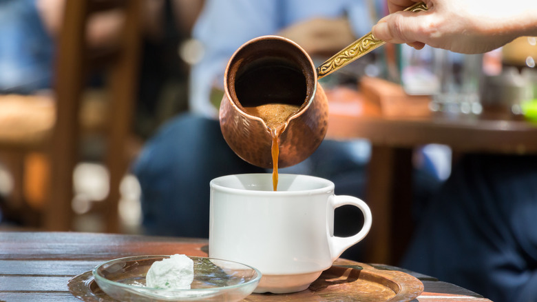 Pouring Greek coffee into cup 