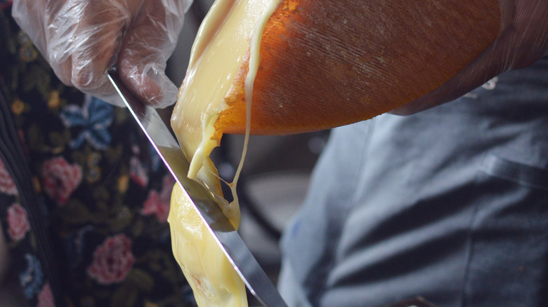 raclette cheese being scraped with knife