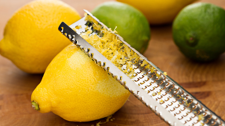 Microplane with lemon zest along with lemons and limes