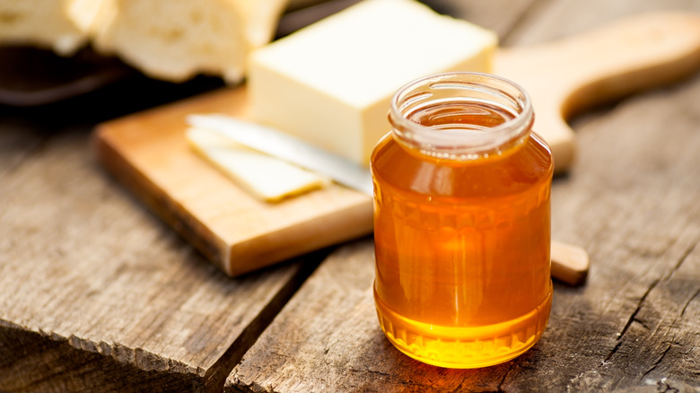 A jar of honey displayed with bread and butter