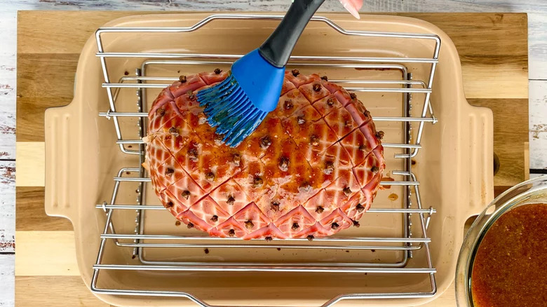 Brushing sticky glaze on clove-studded ham