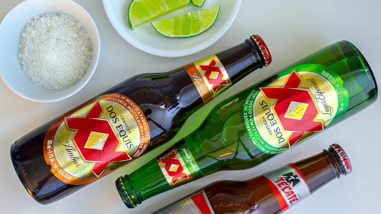 Dos Equis Lager bottles on table with lime and salt