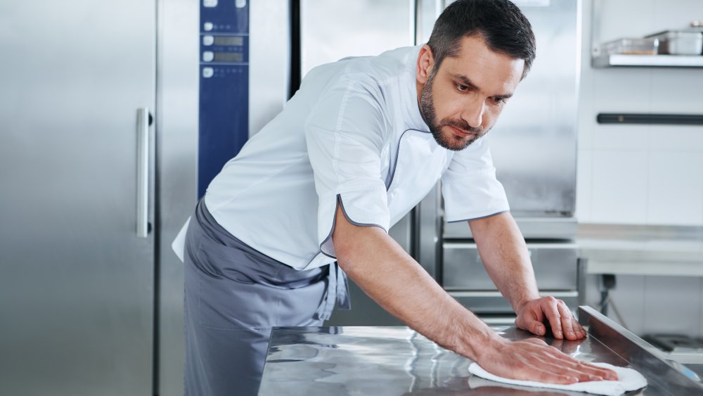 Man cleaning kitchen after prepping burgers