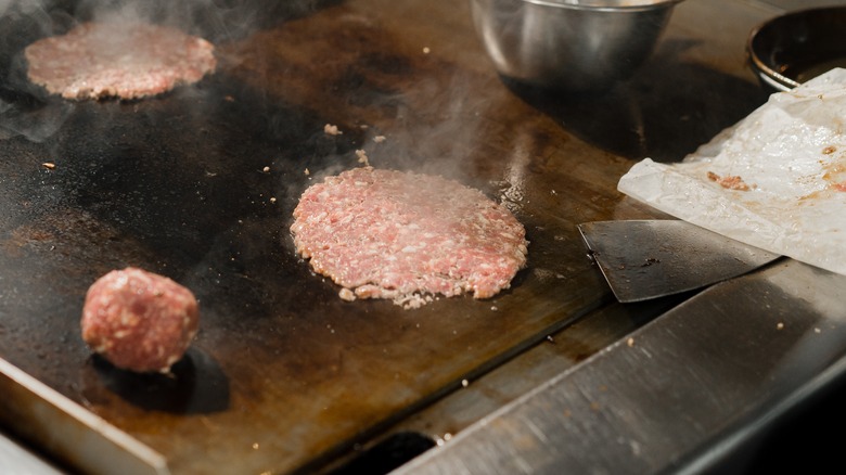 Smash burger on griddle with spatula 