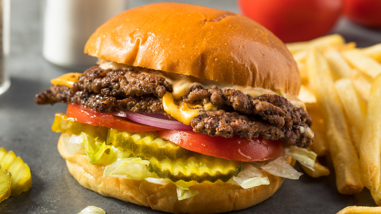 Smash burger in bun with pickles, tomato, red onion, and cheese