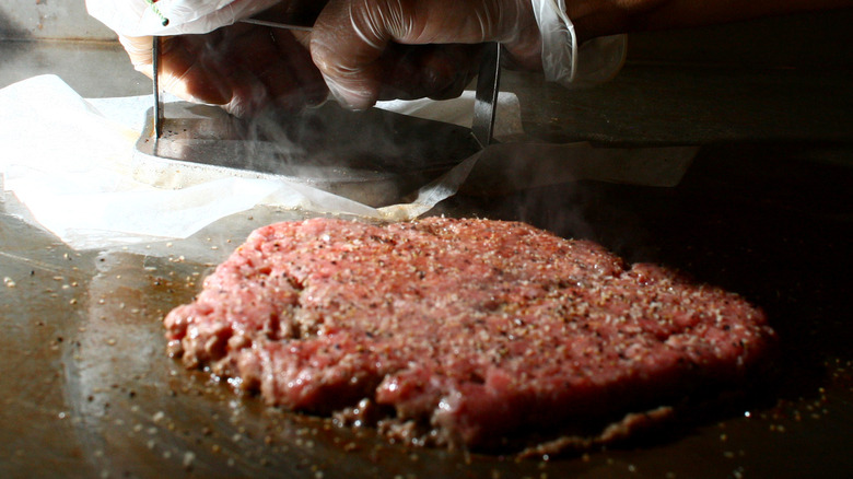 Pressing smash burger on griddle