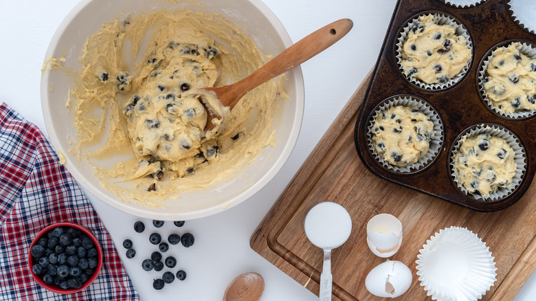 Blueberry muffin batter in bowl next to muffin tin