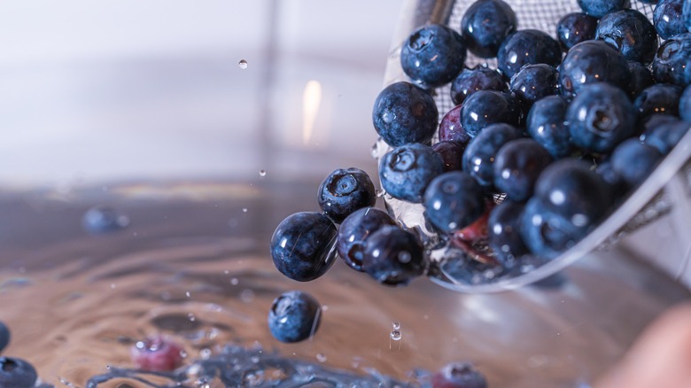 Blueberries splashing into water