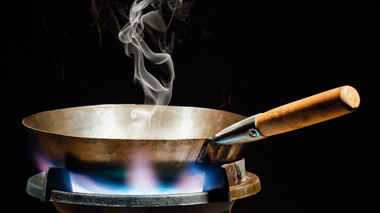 wok on a gas burner with steam rising