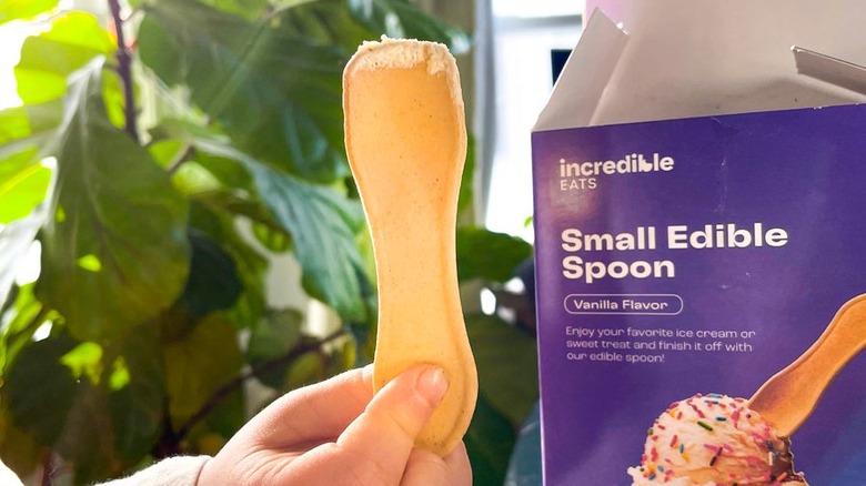 Child's hand holding an edible spoon with the box in the background