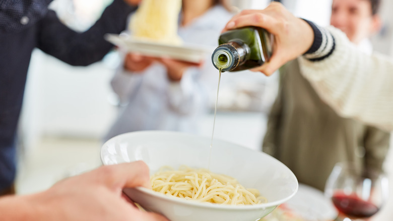 Pouring olive oil on pasta