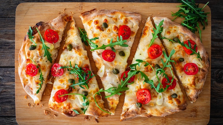 olive oil and garlic on pizza base on wooden board