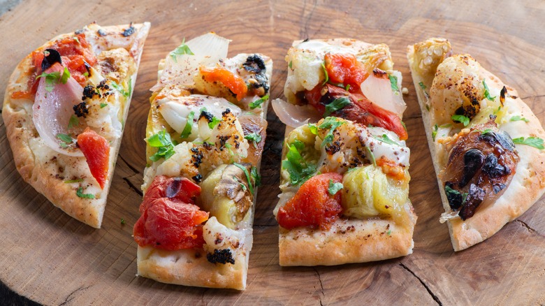 tahini sauce pizza with vegetables on wooden board