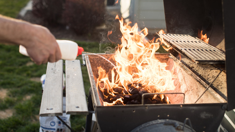 Person lighting a grill with lighter fluid