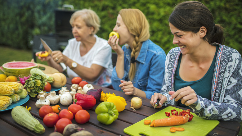 People chopping vegetables and fruits outside