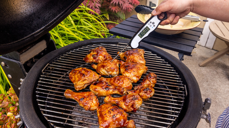 Person checking meat temperature on the grill