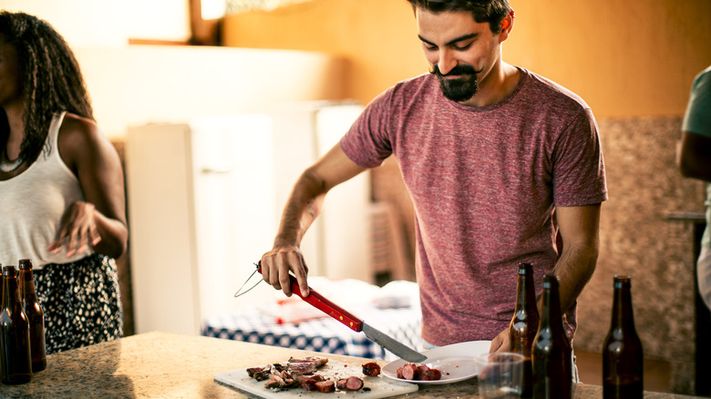 Man with mustache and beard cutting sausages