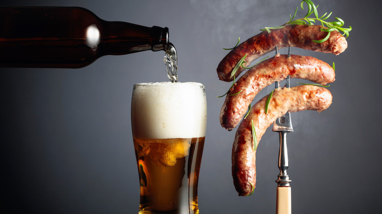 Beer pouring into glass next to sausages on skewer