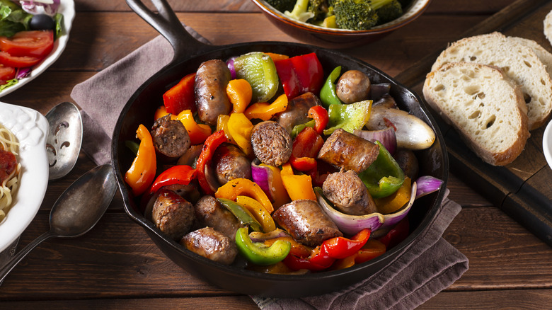 brats in skillet with sliced pepper and onion