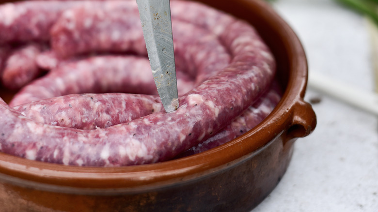 knife poking holes in sausage