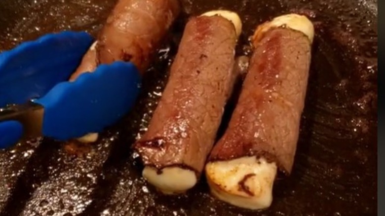 Roast beef wrapped around string cheese in pan