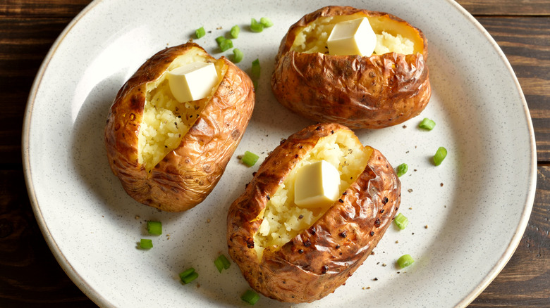 three baked potatoes on plate