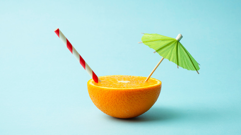 Half orange with straw and drink parasol