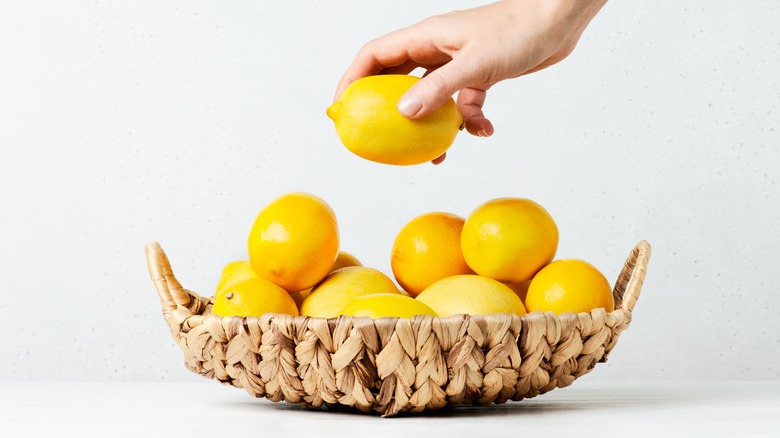 Basket of lemons, one in a hand