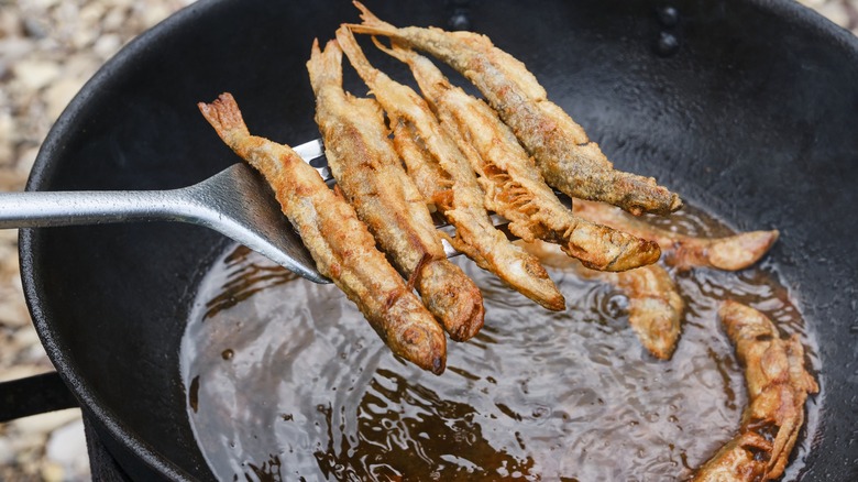 spatula lifting fried fish out of hot pan