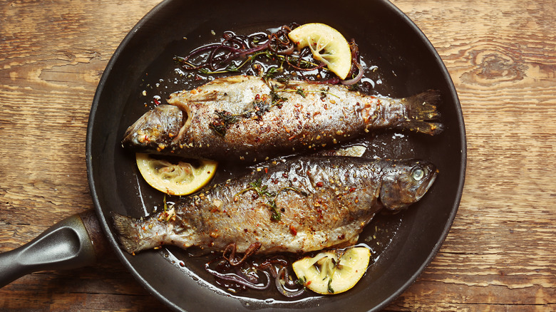 two whole fish in a pan frying