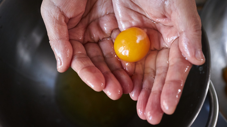 Hands holding egg yolk