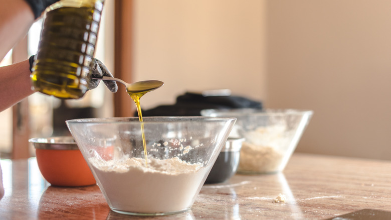 Hand pouring oil into bowl