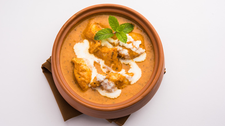 butter chicken with drizzle of sauce in pot