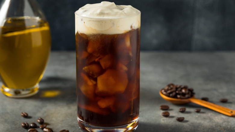 Olive oil iced coffee with olive oil and spoonful of coffee beans