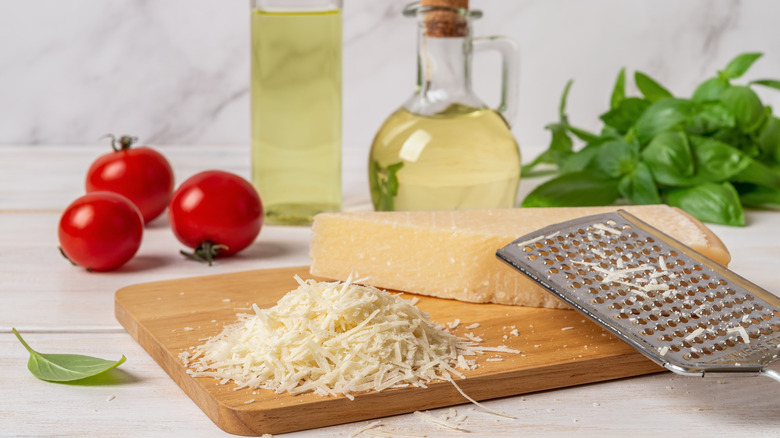 Grated Parmesan with cheese grater on wooden cutting board