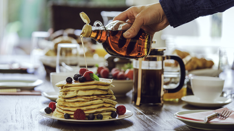 pouring maple syrup on pancakes