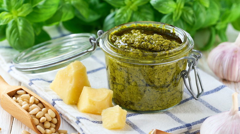 A jar of pesto with ingredients on the side