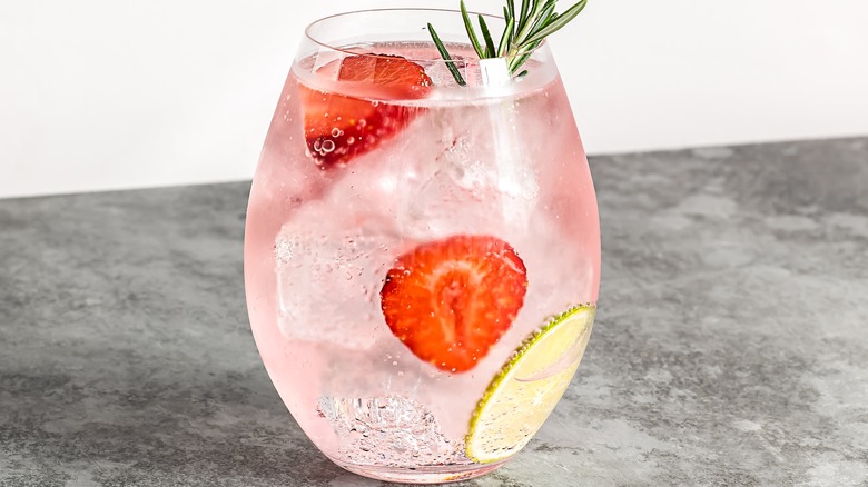 pink gin and tonic with strawberries and herbs