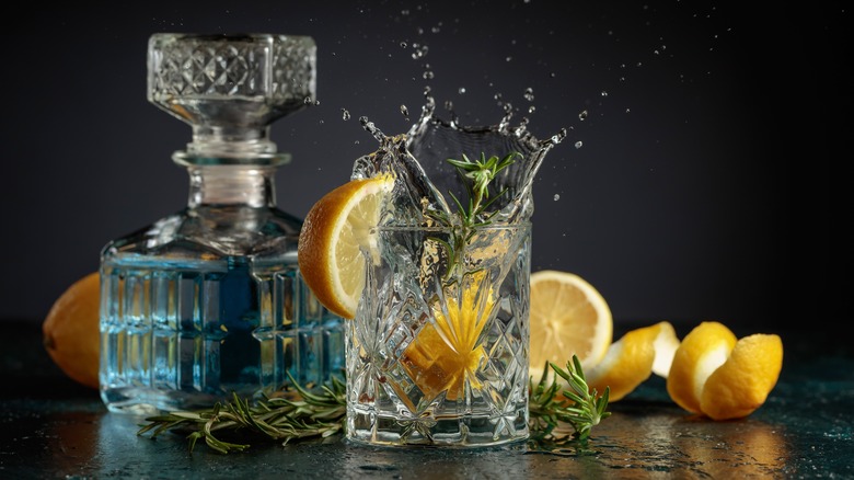 gin and tonic splashing in glass with decanter