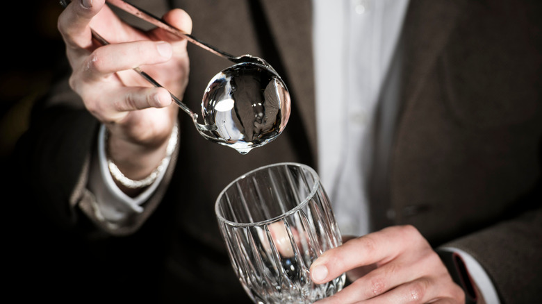 spherical ice cube with tongs and glass