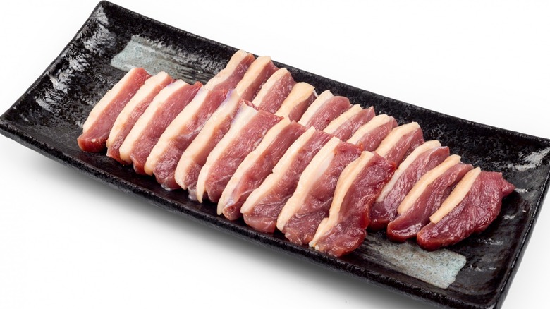 duck bacon slices on black tray