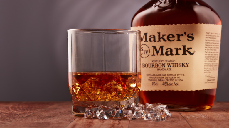 Glass of whiskey next to Maker's Mark